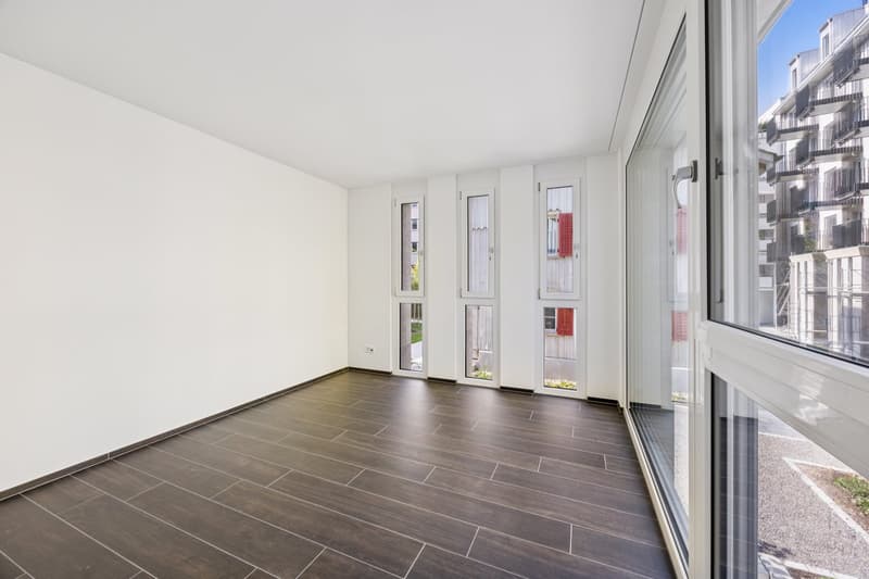 White walls, wooden floor, multiple glass doors leading to balcony