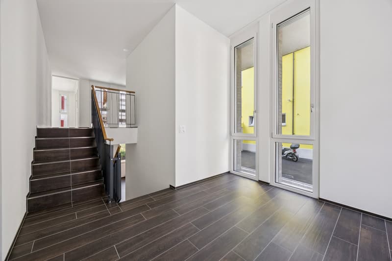 Empty hallway, wooden stairs, floor windows, white walls, brown tiled flooring