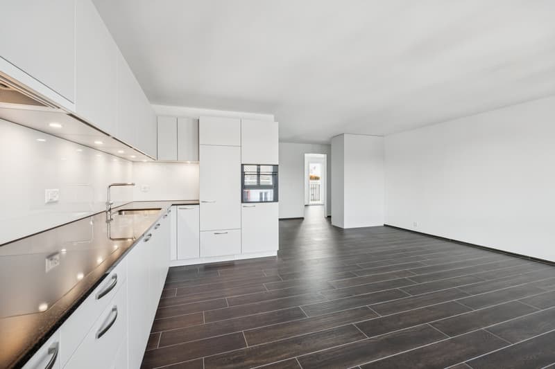Modern kitchen with white cabinets, granite countertops, stainless steel faucet, and tile flooring.