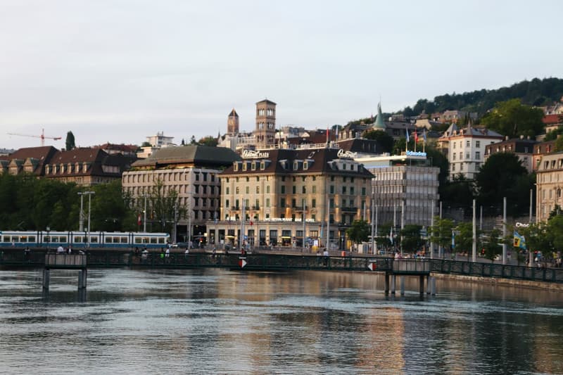 Cityscape view of buildings across a river, large hotel with many windows, bridge with people walking
