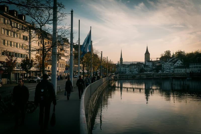 Urban cityscape, river, people walking, tall buildings, clear sky