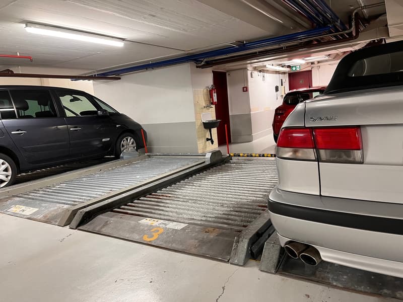underground parking lot, metal parking lift, red car, black car, silver car