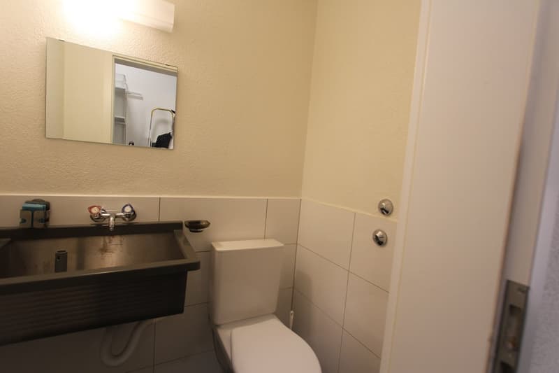 small bathroom with sink, toilet, mirror, and tiled walls
