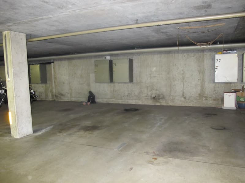underground parking lot, concrete walls, numbered parking spots, electrical boxes, motorcycle