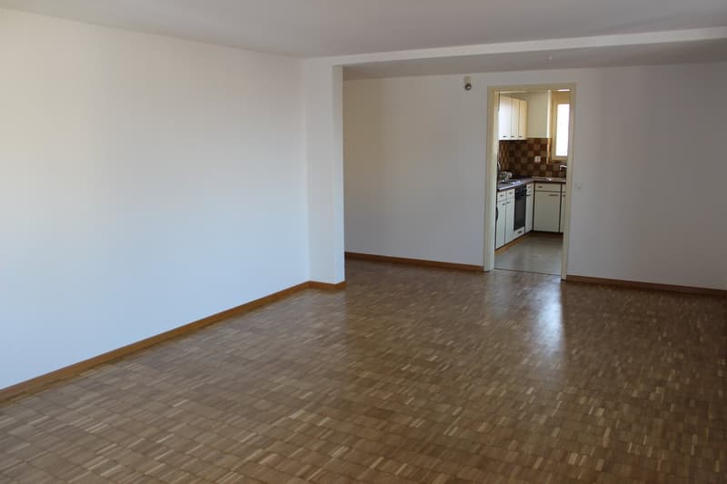 empty room, wooden floor, white walls, open door to kitchen