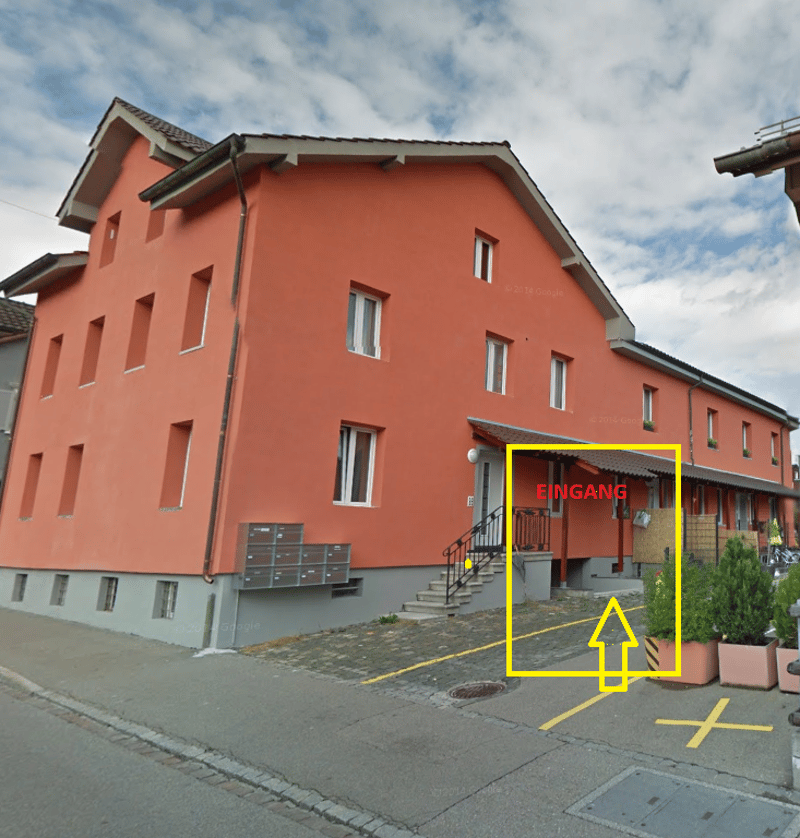 three-story apartment building, orange facade, gray base, gray roof, multiple windows, staircase entrance, mailboxes, small front garden