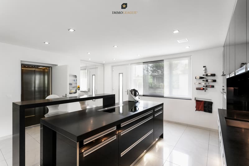 Die Küche in Hochglanzschwarz und mit Edelstahlabdeckung strahlt eine elegante, moderne Atmosphäre aus.
