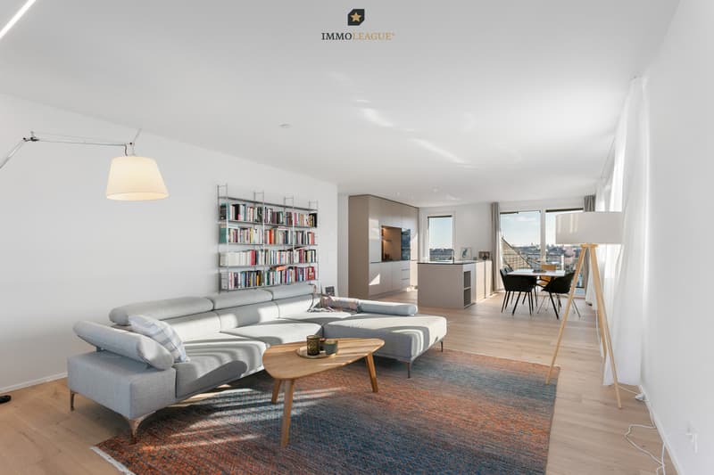 Fliessend schliesst der Wohnbereich an Küche und Essbereich an. Grosszügige Fensterflächen und der direkte Zugang zur Westterrasse verleihen dem Raum Tiefe.