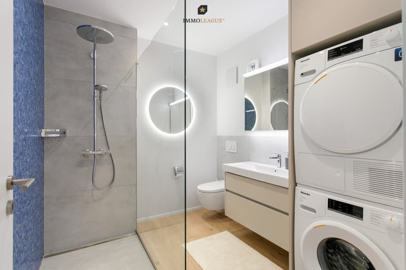 Funktional und elegant zugleich: Das Badezimmer überzeugt mit bodenebener Dusche, hochwertigen Materialien und integriertem Waschturm.