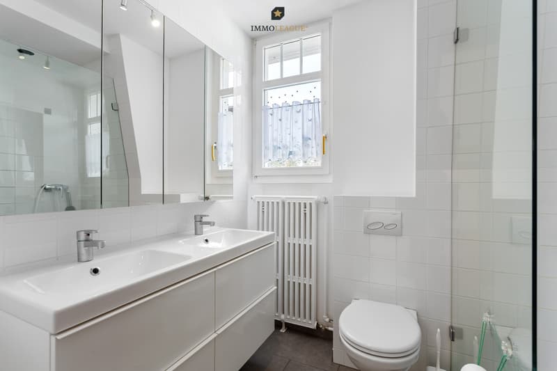 Das modernisierte helle Badezimmer überzeugt mit Doppelwaschtisch, begehbarer Dusche und zeitlosem Design.