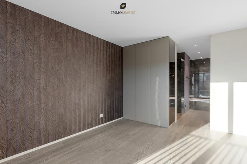 Das Schlafzimmer bietet direkten Zugang zum grossen Bad. Der harmonisch integrierte Einbauschrank rundet das exklusive Raumgefühl ab.