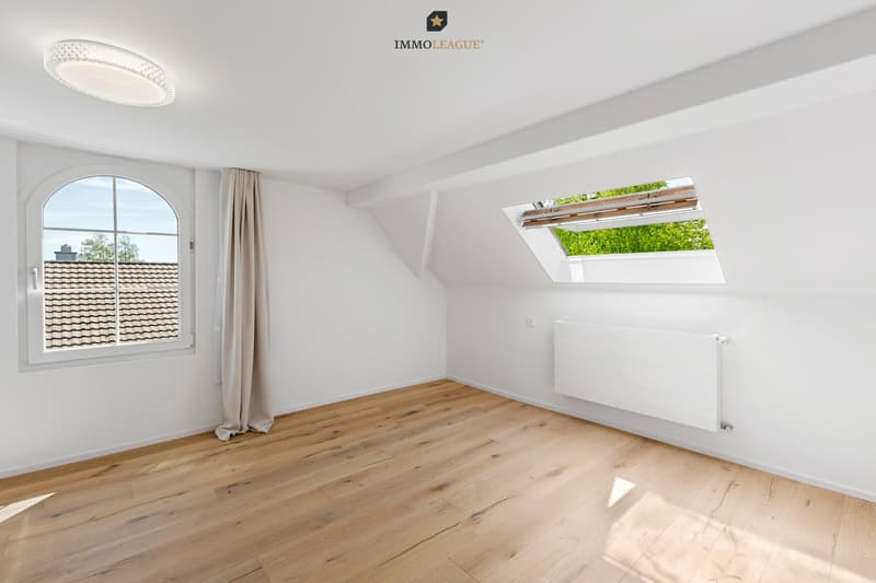 Lichtdurchflutetes Dachzimmer mit stilvollen Rundbogenfenstern und eleganten Dachschrägen, ein einzigartiger Raum mit besonderem Charme und aussergewöhnlicher Wohnqualität.