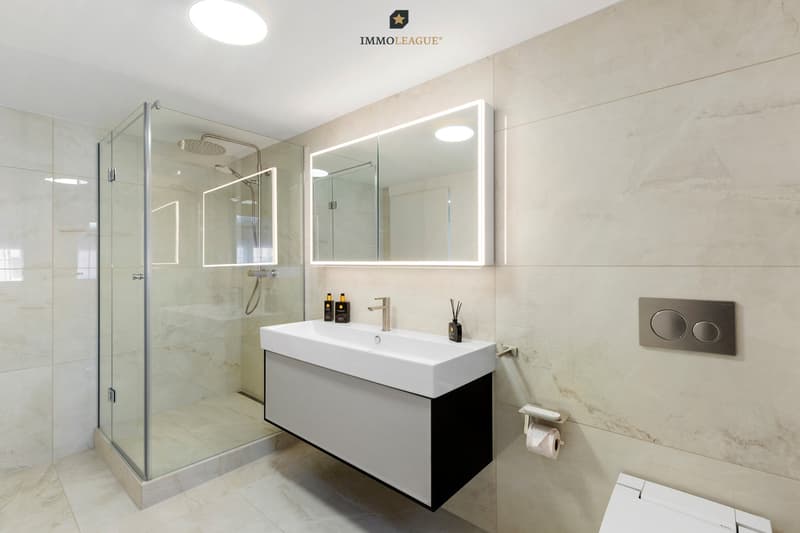 Elegantes Badezimmer mit begehbarer Regendusche und beleuchtetem Spiegel.