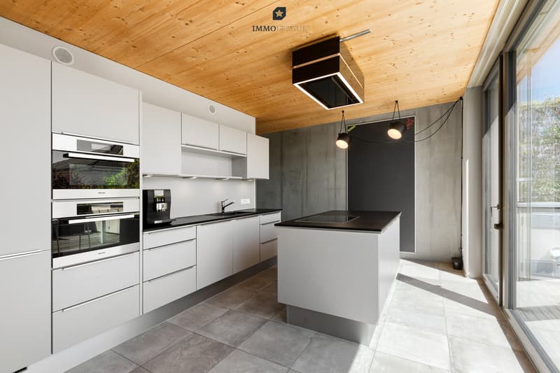 Die Küche mit Kochinsel überzeugt mit einem klaren, durchdachten Design. Sie ist ausgestattet mit Geräten von Miele und einer Abzugshaube von Berbel.