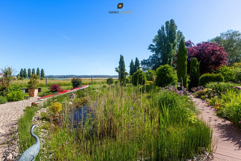 Biotop, blühende Gartenbereiche und die sonnige Terrasse prägen eine aussergewöhnlich stimmungsvolle Gartenlandschaft mit Blick bis zum See.