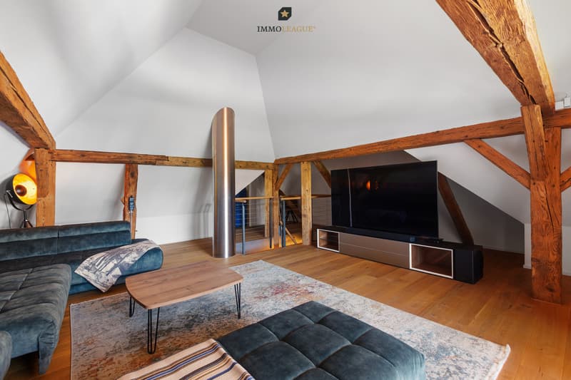 Exklusiver Wohnkomfort unter dem Dach - stilvolle Lounge mit imposanten Holzbalken und modernem Design