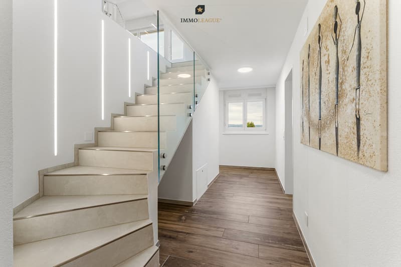 Beleuchtung als Gestaltungselement: Feine LED-Lichtlinien führen die Treppe hinauf. Integrierte Einbauschränke bieten Stauraum, wo man ihn braucht.