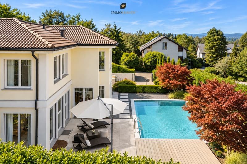 Pool, Garten und Terrasse bilden einen privaten Aussenbereich mit viel Platz zum Entspannen und Geniessen. / a house with a swimming pool and an umbrella