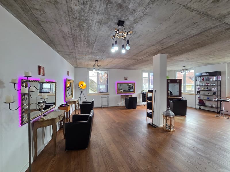 Large room with hardwood floors, several armchairs, mirrors, tables, decorative items, purple and white lights, large windows