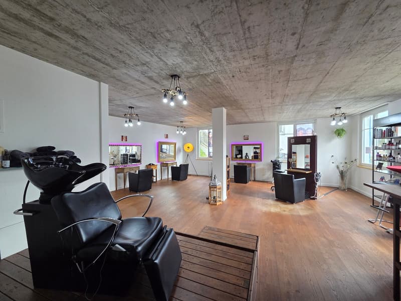 modern salon with white walls, wooden floors, black leather chairs, hanging lamps, mirrors, wooden tables, decorative items