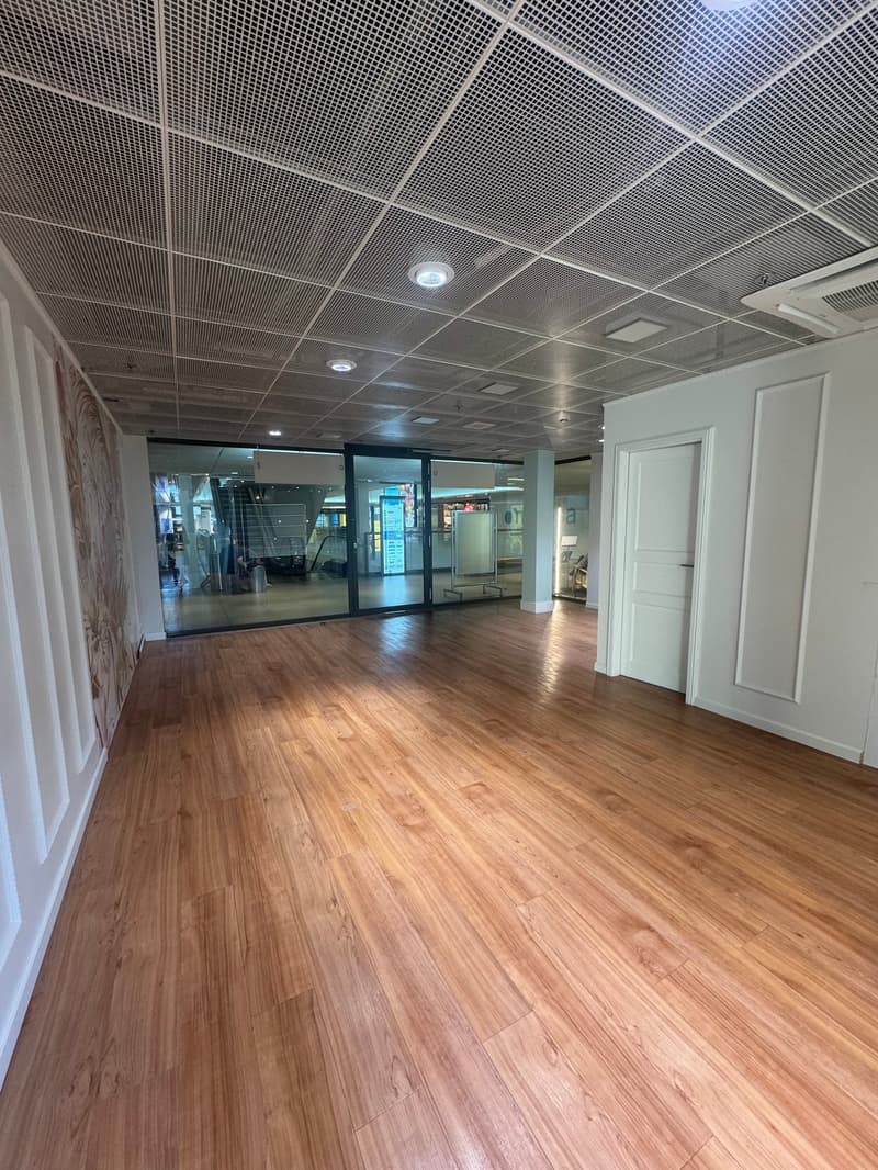 empty room, hardwood floors, metal grid ceiling, large glass walls, two doors