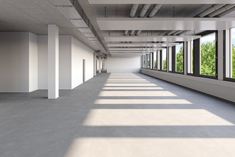 Open corridor, white walls, concrete floor, large windows, sunlight from windows