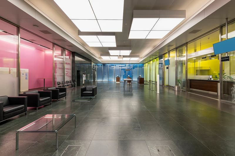 Large open lobby with glass walls, colorful accents, modern furniture, and a reception desk