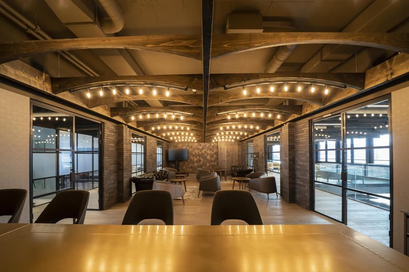 Open floor plan with wooden beams, glass walls and doors, leather chairs, glass tables, tables with chairs, mounted monitor, carpet, and windows