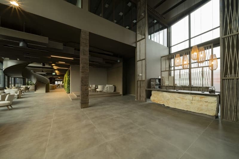 modern design, large space, reception desk, hanging lamps, couches, staircase, plants, wooden walls, large windows