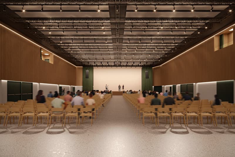 large hall, wooden chairs arranged in rows, stage, projector screen, brown wooden walls, high ceiling with lighting fixtures