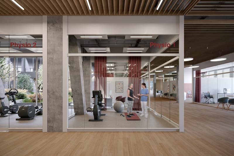 Wooden floor, two women standing, two exercise bikes, one treadmill, exercise ball, red mat, mirrors on walls