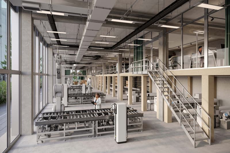 Large industrial facility with multiple floors, numerous machines, large glass windows, metal staircases, office areas