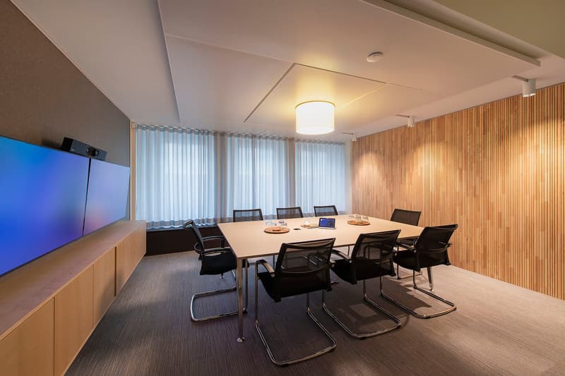 conference table, black chairs, mounted TV, white curtains