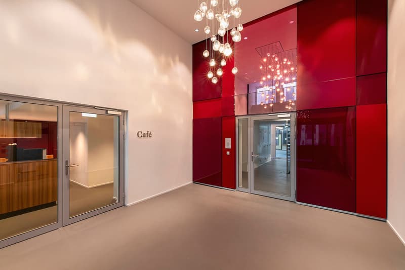 entrance lobby with red wall panels, glass doors, chandelier, cafe sign