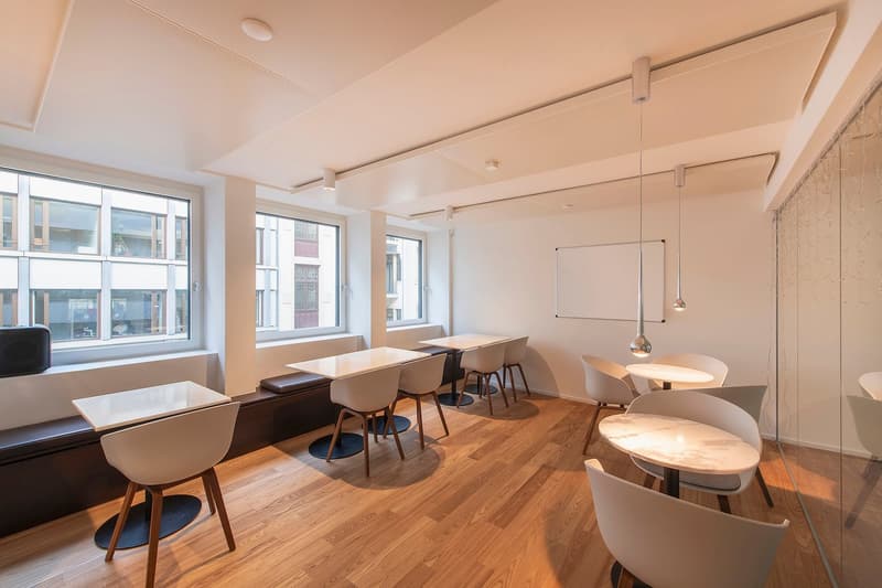 modern office room, white walls, wooden floors, white chairs, desks, large windows, glass wall, view of buildings outside