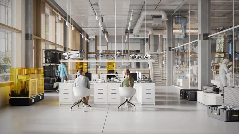 modern office space with white desks, chairs, large windows, yellow 3D printers, storage boxes, and a staircase