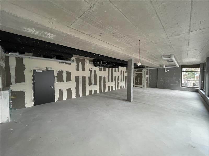Empty room, concrete floor, unfinished walls, door, windows, pipes on ceiling