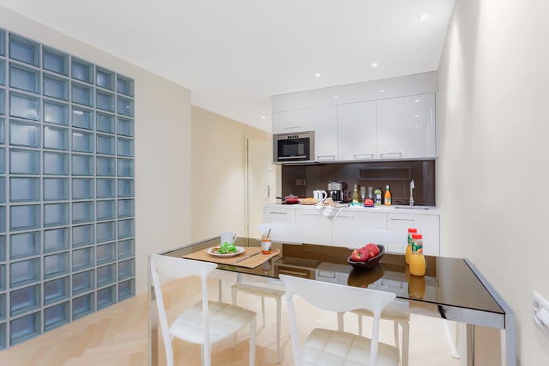modern design, white cabinets, stainless steel appliances, glass table, white dining chairs, countertop with food items