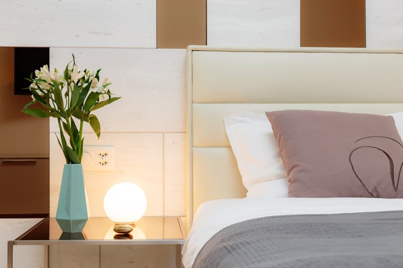 a bedroom with a double bed, nightstand with a lamp and vase, and white walls