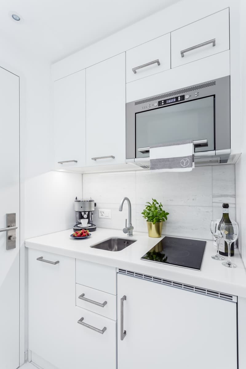 compact kitchen, white cabinets, modern appliances, sink, electric stove, dishwasher, microwave