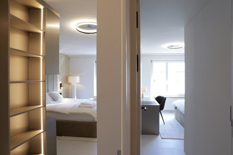Modern bedroom with bed, built-in wardrobe, desk, lamps, and windows