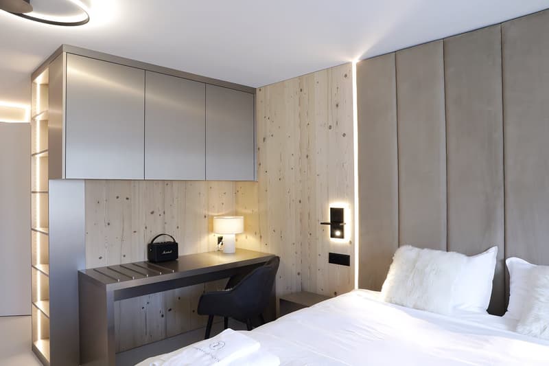 bed, desk, chair, white fur pillows, bedside table, small lamp, small shelf, white linens, white wooden wall