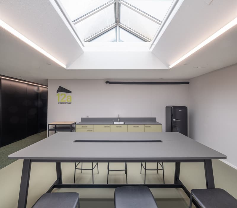 skylight, gray wall, kitchen area with refrigerator, sink, cabinets, countertop, bench, table, seating, logo on the wall