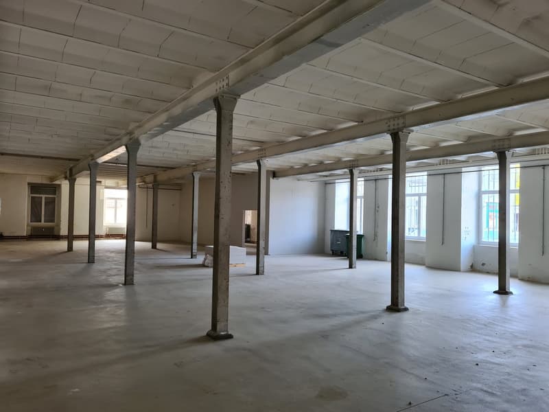 Empty room with concrete floor, metal beams, and windows