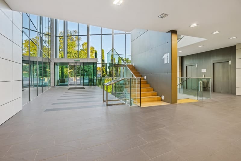 large entrance, glass walls, tile flooring, large staircase, exit