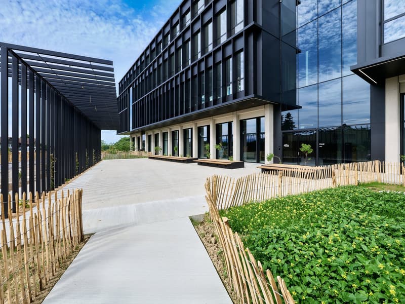 Modern building with black facade, glass windows, and entranceway.