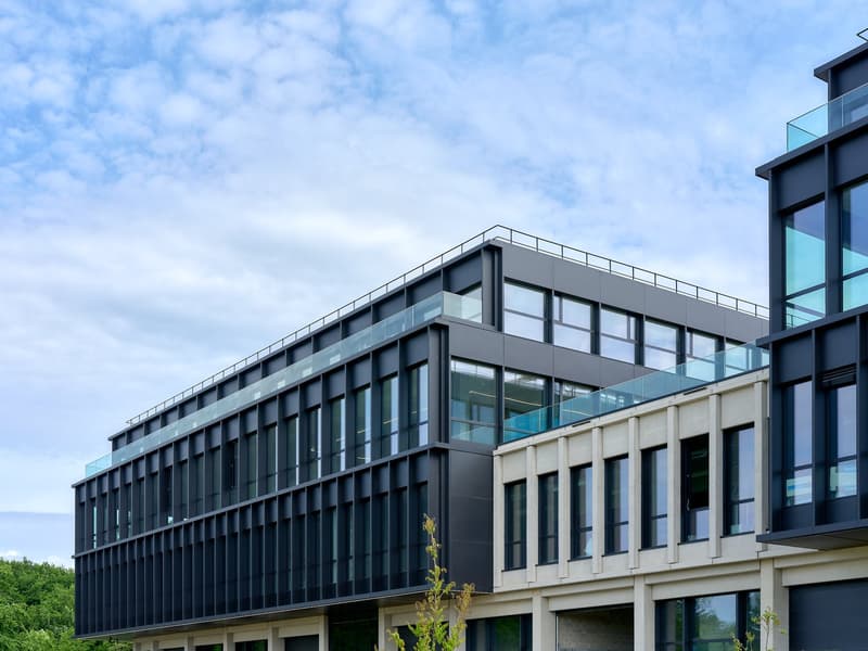 Modern office building, black and grey facade, multiple floors, large glass windows, terraces on top floors