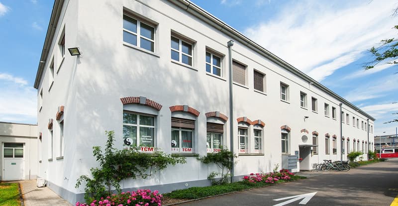 Two story white house with brick detail, multiple windows, bicycles parked in front.