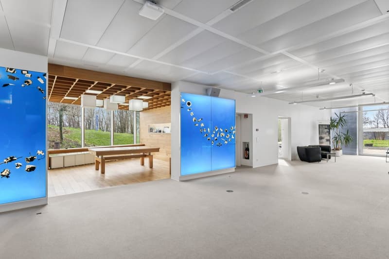 large open space, wooden table, blue glass wall, white ceiling, large windows, carpeted floor