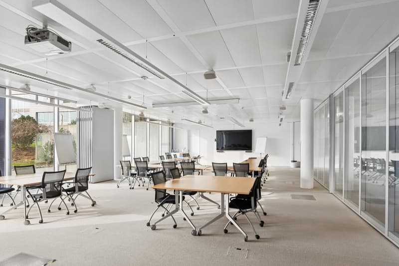 modern office room with glass walls, white ceiling, carpeted floor, tables, chairs, whiteboards, projector